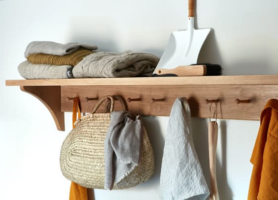 Shaker-style oak peg rail with shelf holding baskets, towels and blankets