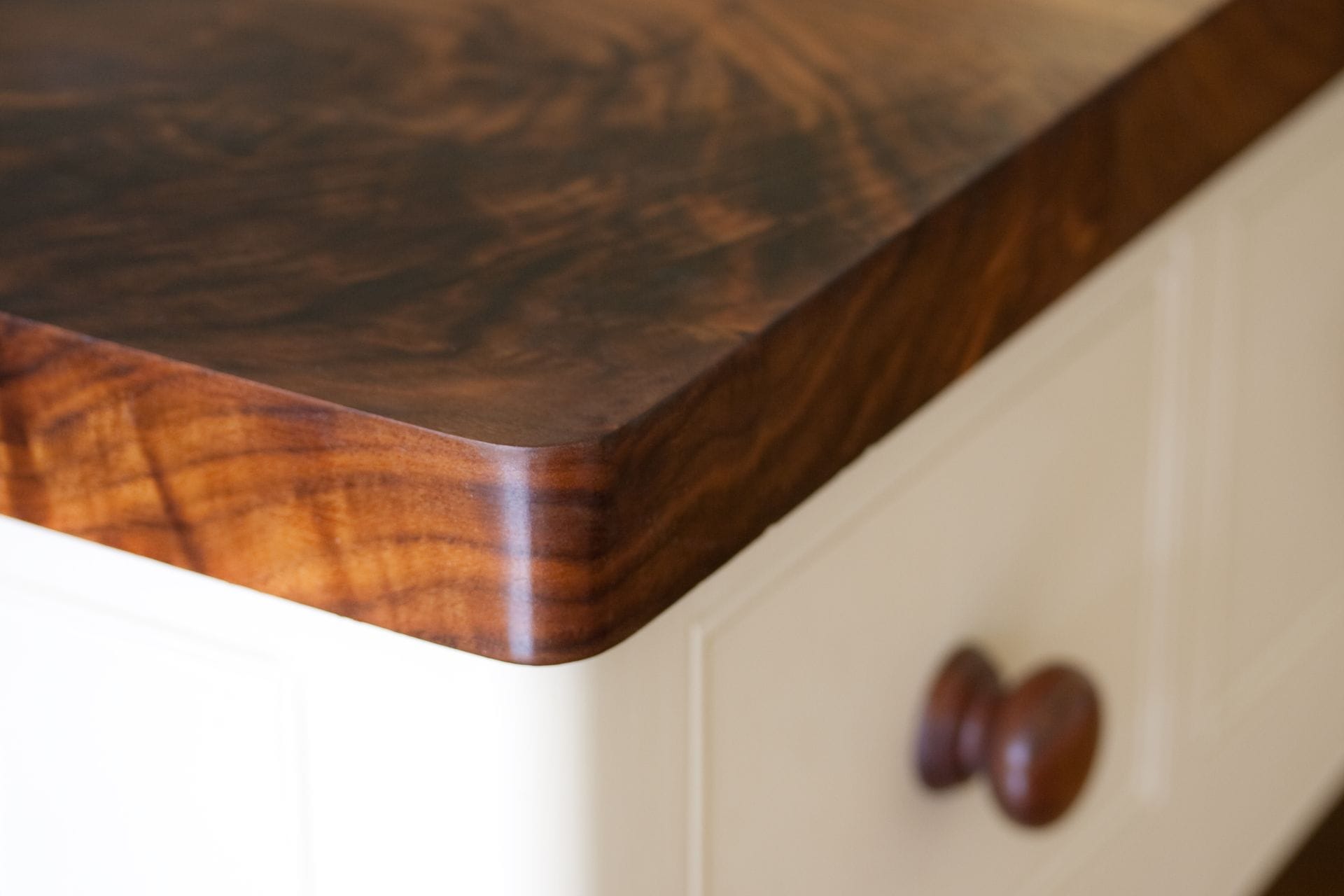 Radius corner on a dark walnut worktop above cream painted drawers