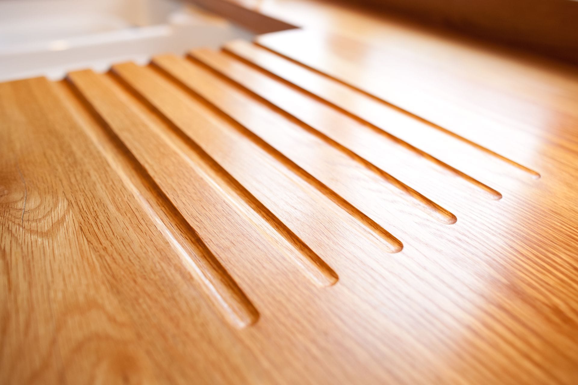 Machined drainage grooves running across an oak worktop beside the sink