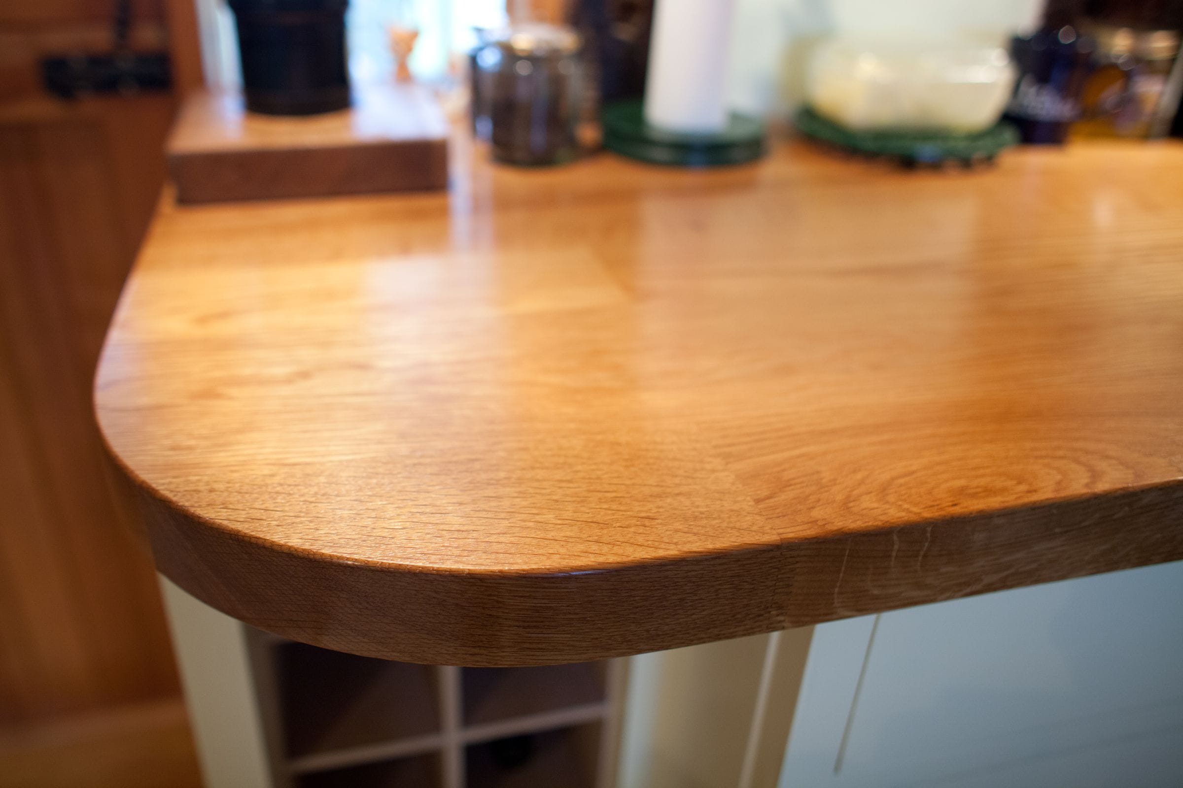 Curved corner of an oiled oak breakfast bar worktop in a kitchen