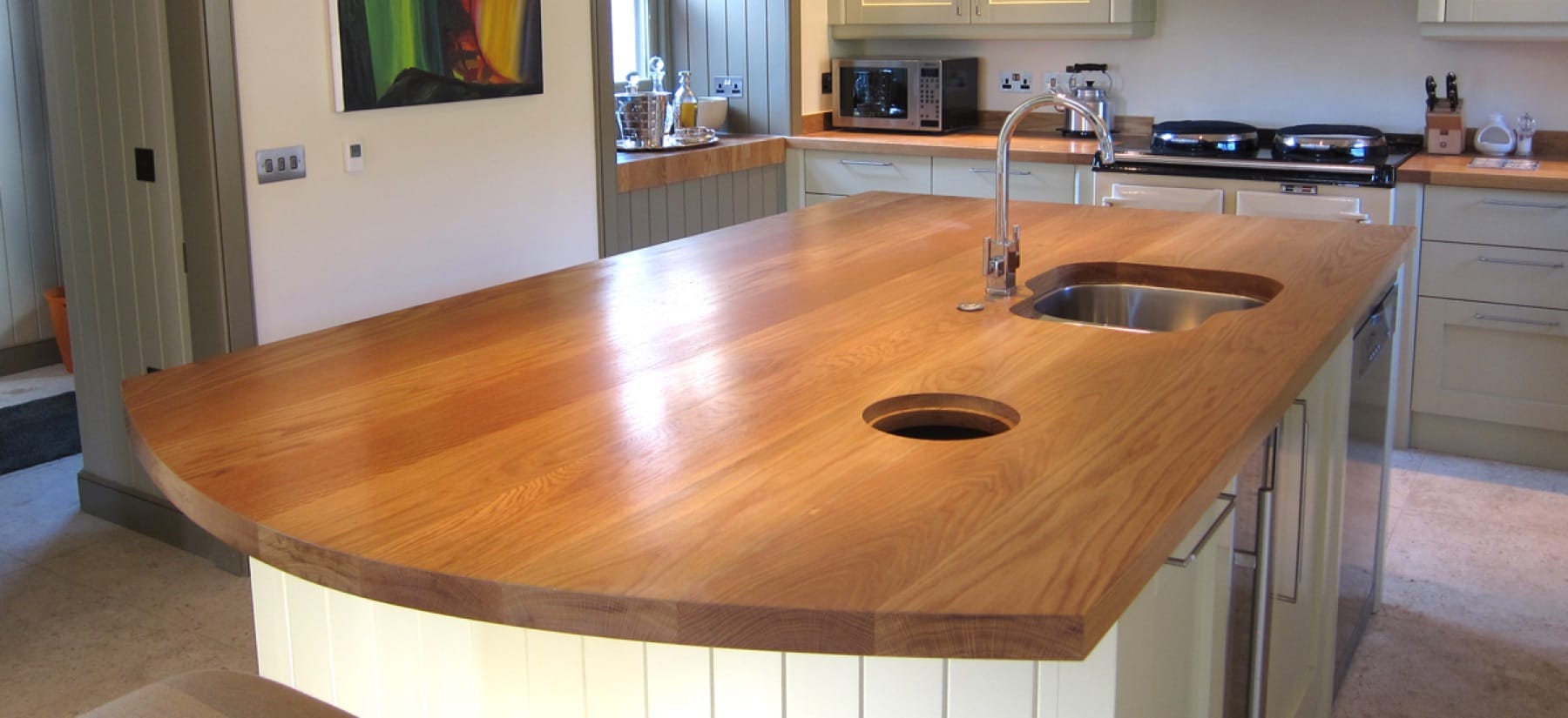 Curved oak worktop on a kitchen island with undermount sink and mixer tap