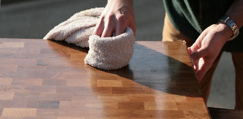 Hand oiling an end-grain walnut worktop with a folded cloth