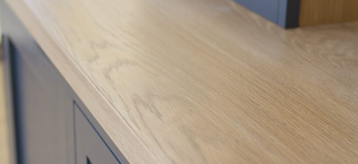 Close-up of a whitewashed oak worktop edge on dark blue cabinets