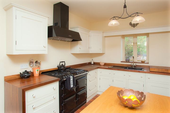 Cream kitchen with dark wooden worktops and a black range cooker