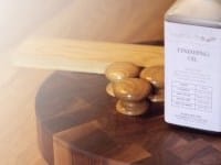 Wooden cabinet knobs and finishing oil bottle on an end-grain chopping board