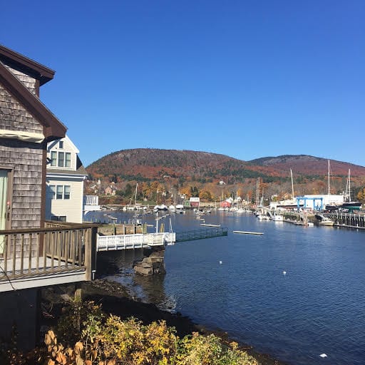 New England harbour with moored boats and autumn-coloured hills beyond