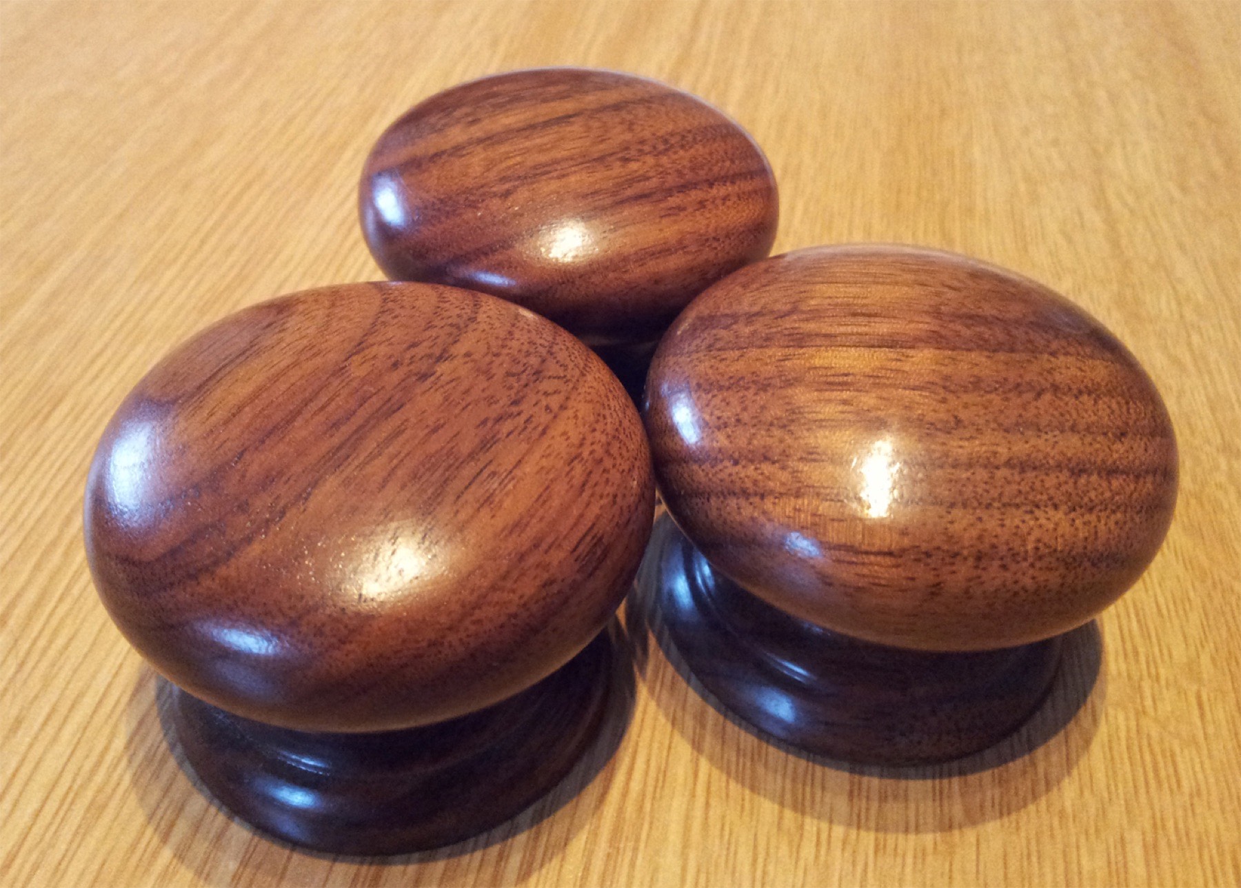 Three hand turned walnut knobs grouped on an oak worktop