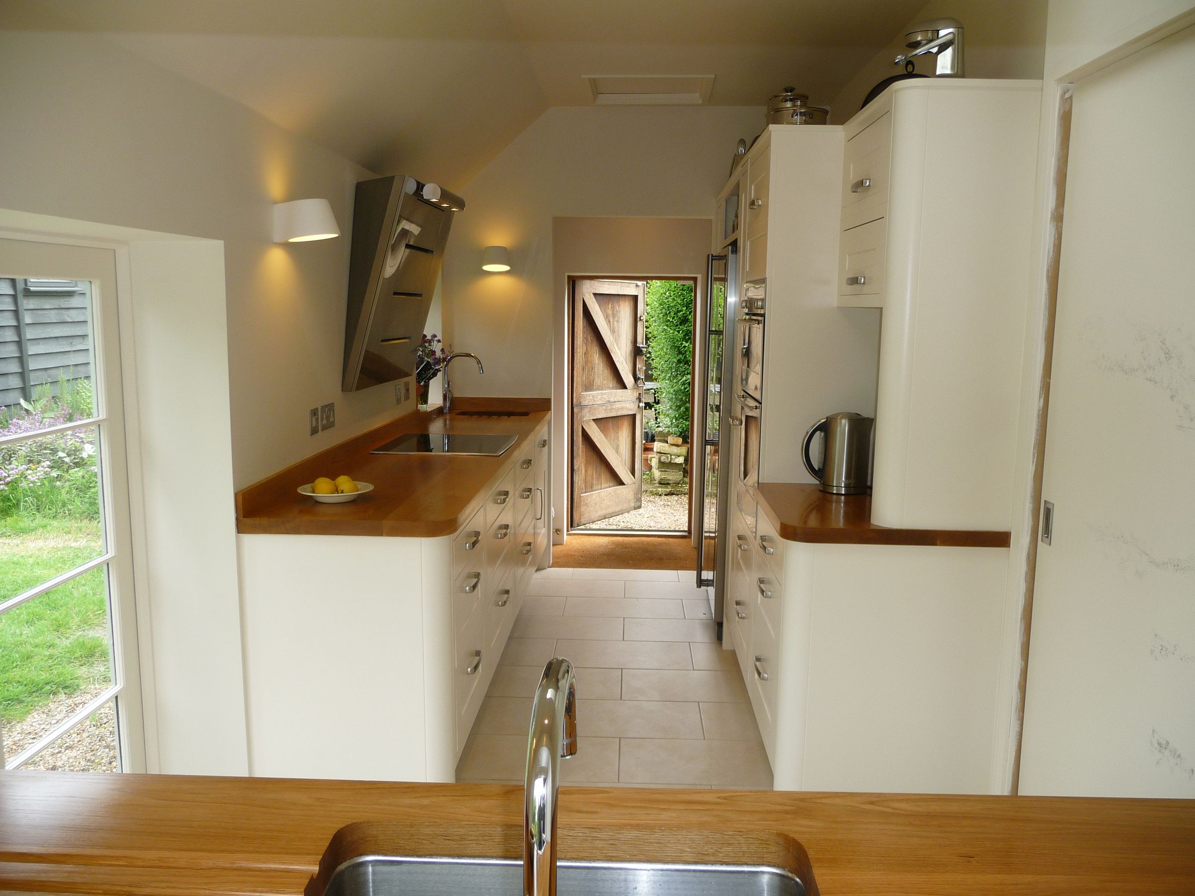 Cream galley kitchen with oak worktops and a stable door open to the garden