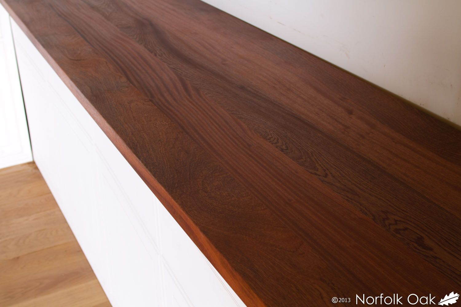 Rich reddish-brown sapele worktop fitted on white kitchen cabinets