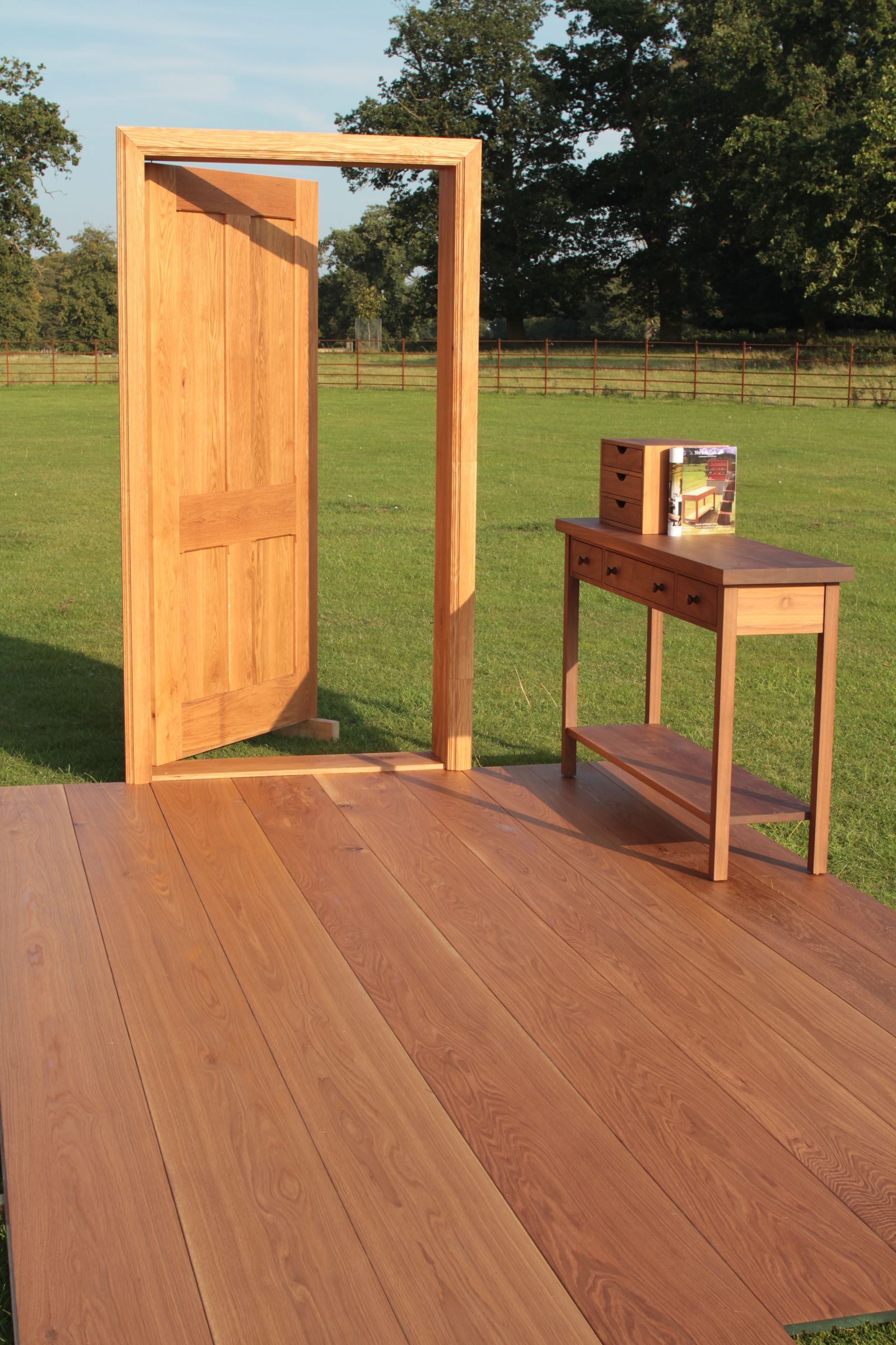 Bespoke oak door and frame displayed outdoors on oak flooring beside a console table