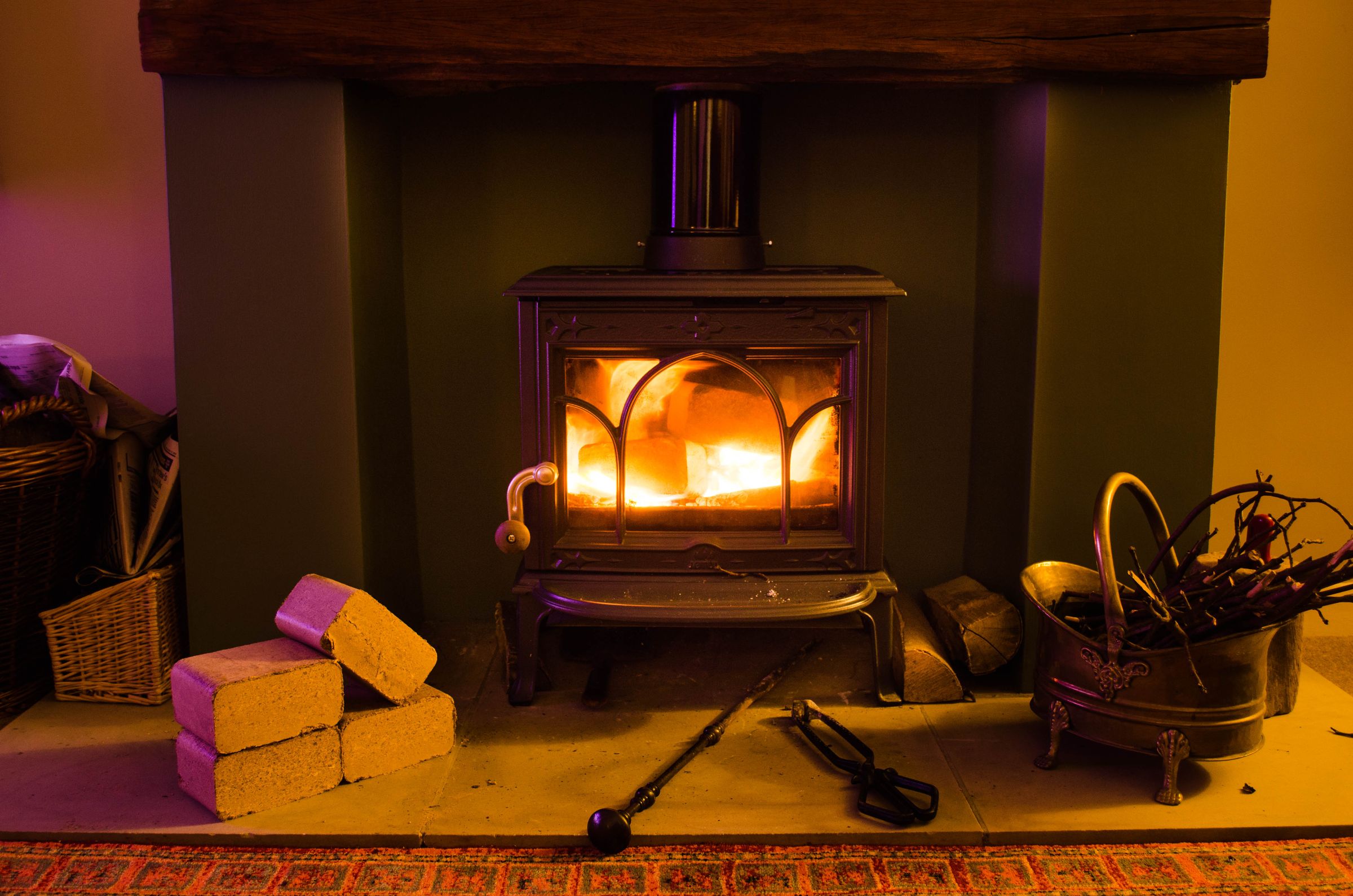norfolk oak briquettes Wood-burning stove alight with hardwood briquettes stacked on the hearth beside it