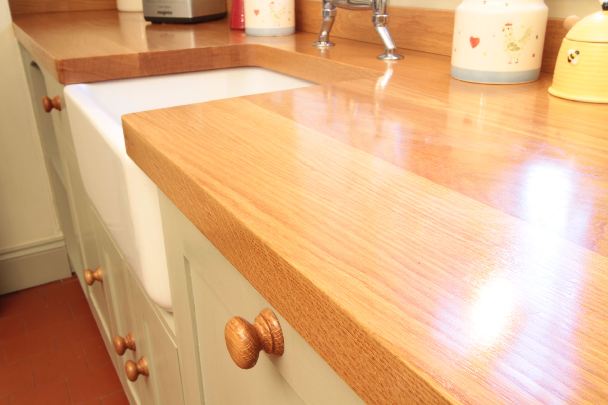 oak worktop Oiled oak worktop edge above a white Belfast sink and cream painted cabinets
