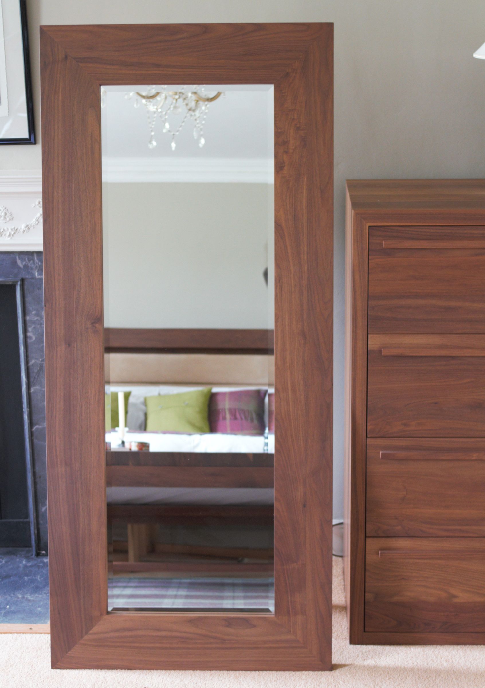 walnut freestanding mirror Tall freestanding walnut-framed mirror leaning beside a matching chest of drawers