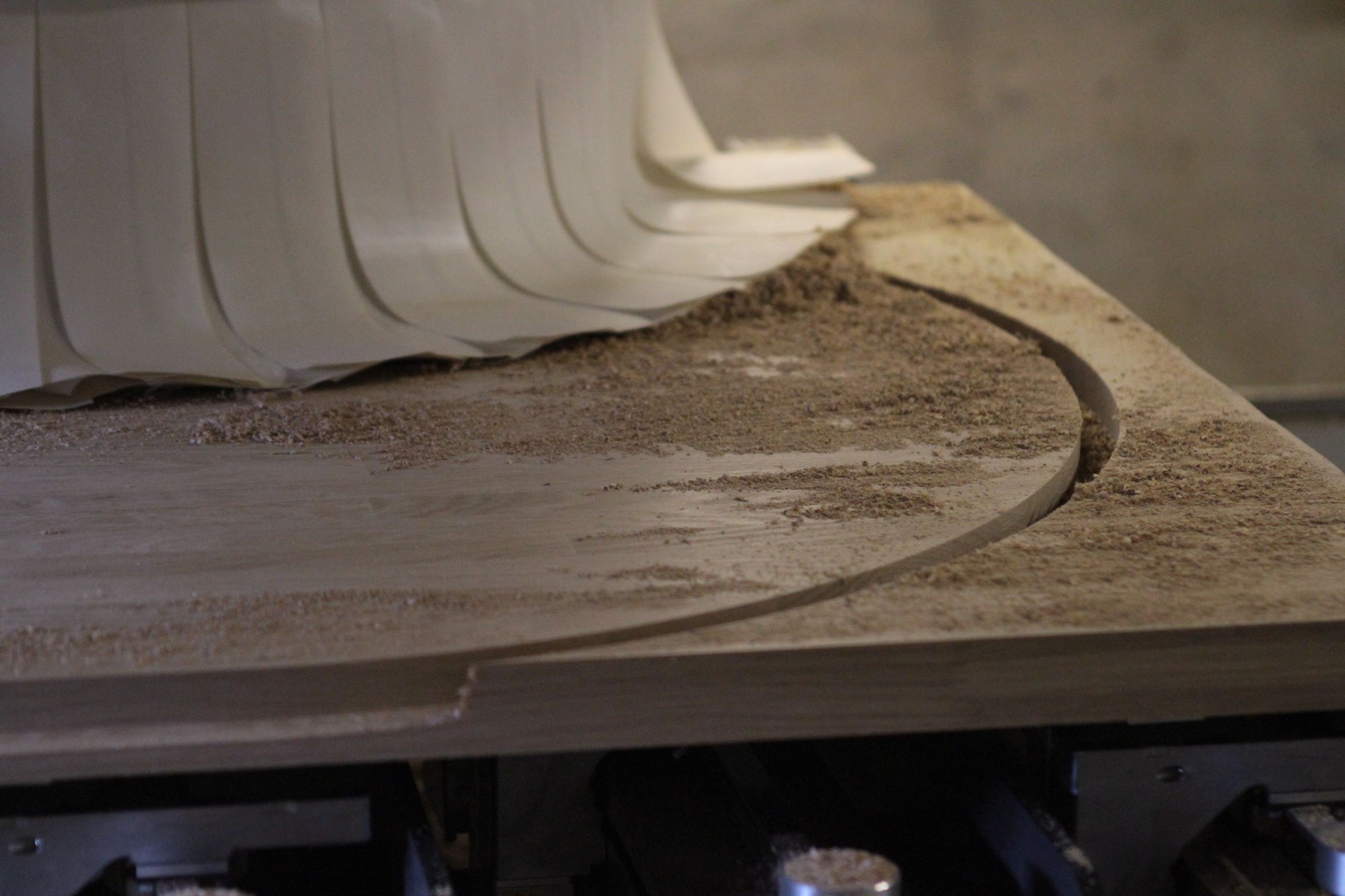 cnc cutting bespoke worktop Curved cut-out being CNC machined into a wooden worktop, sawdust on the surface