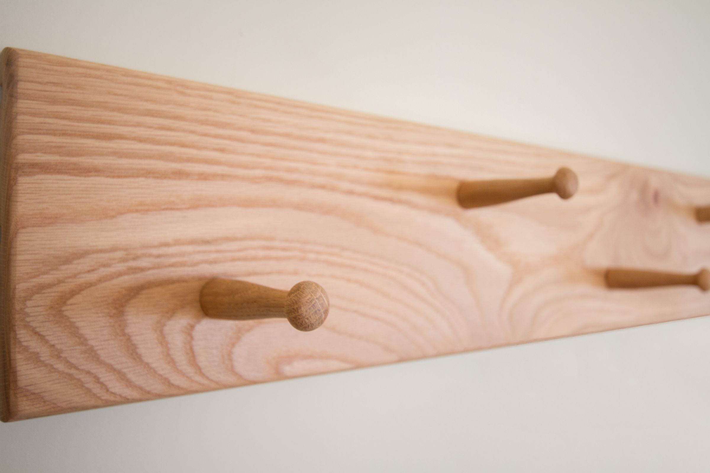 staggered peg rail Oak Shaker peg rail with pegs staggered at two heights, seen close up