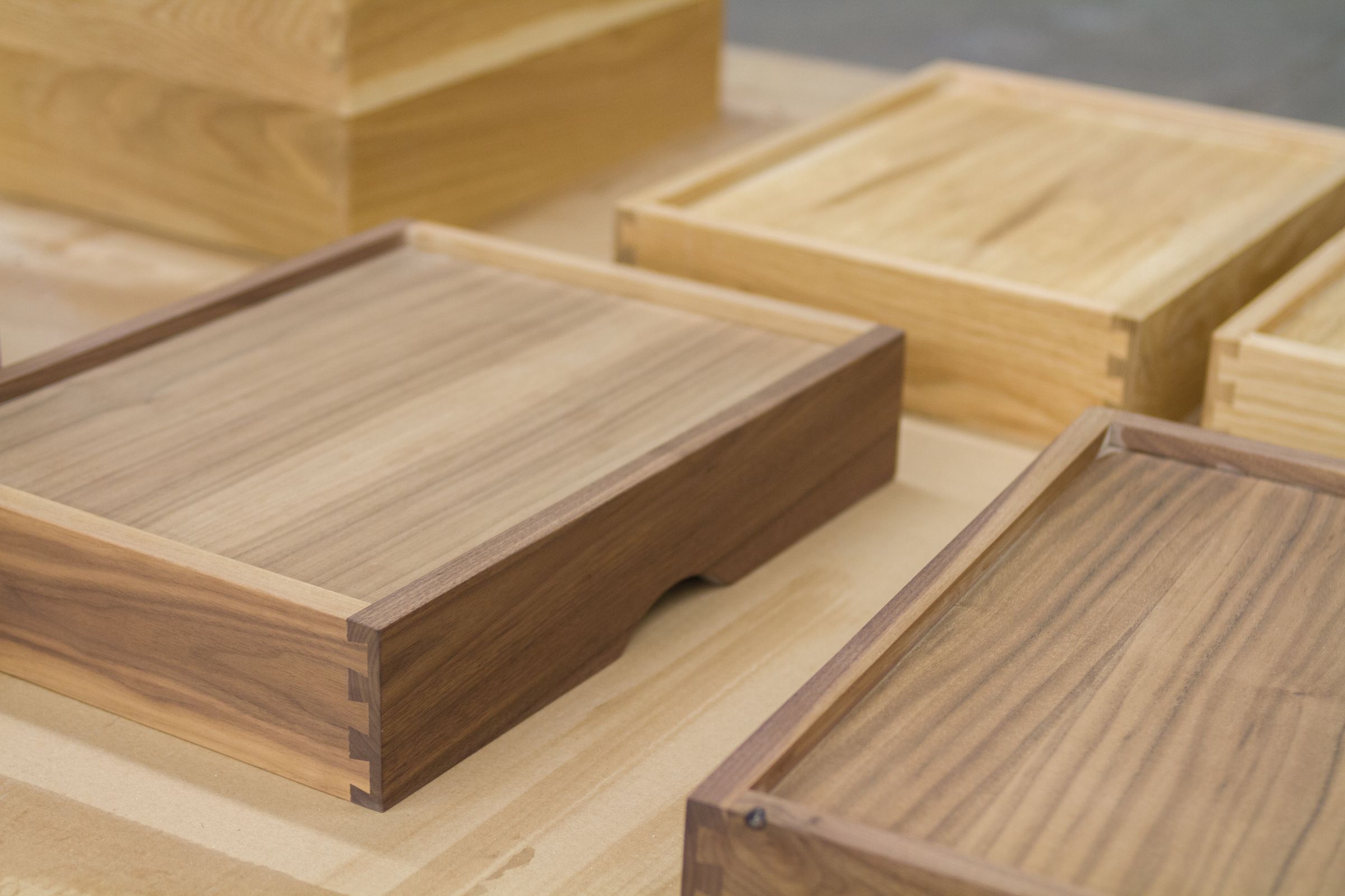 filing drawer boxes Dovetailed walnut and oak drawer boxes on a workshop bench after final sanding