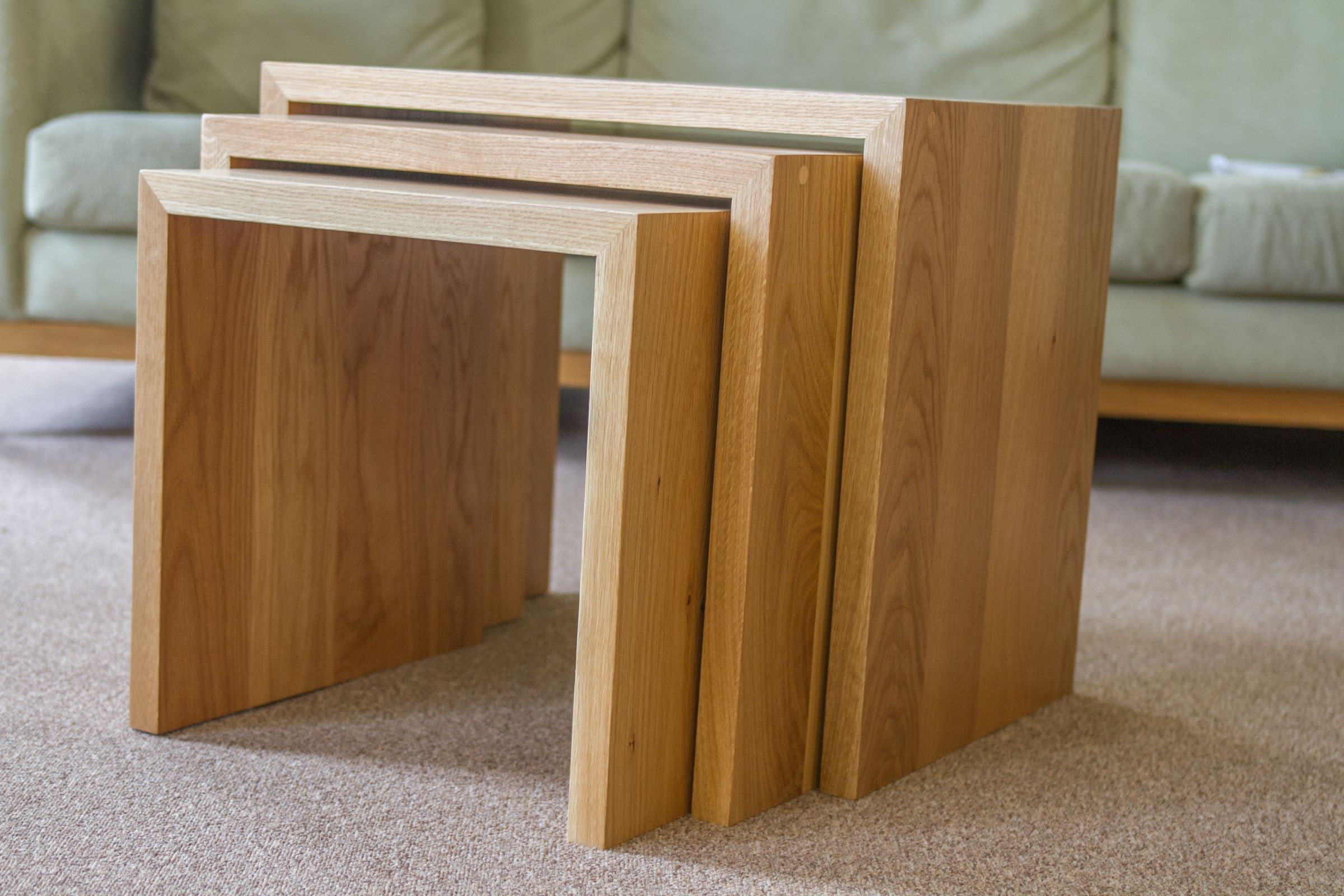 oak coffee table nest Nest of three solid oak coffee tables in front of a pale green sofa