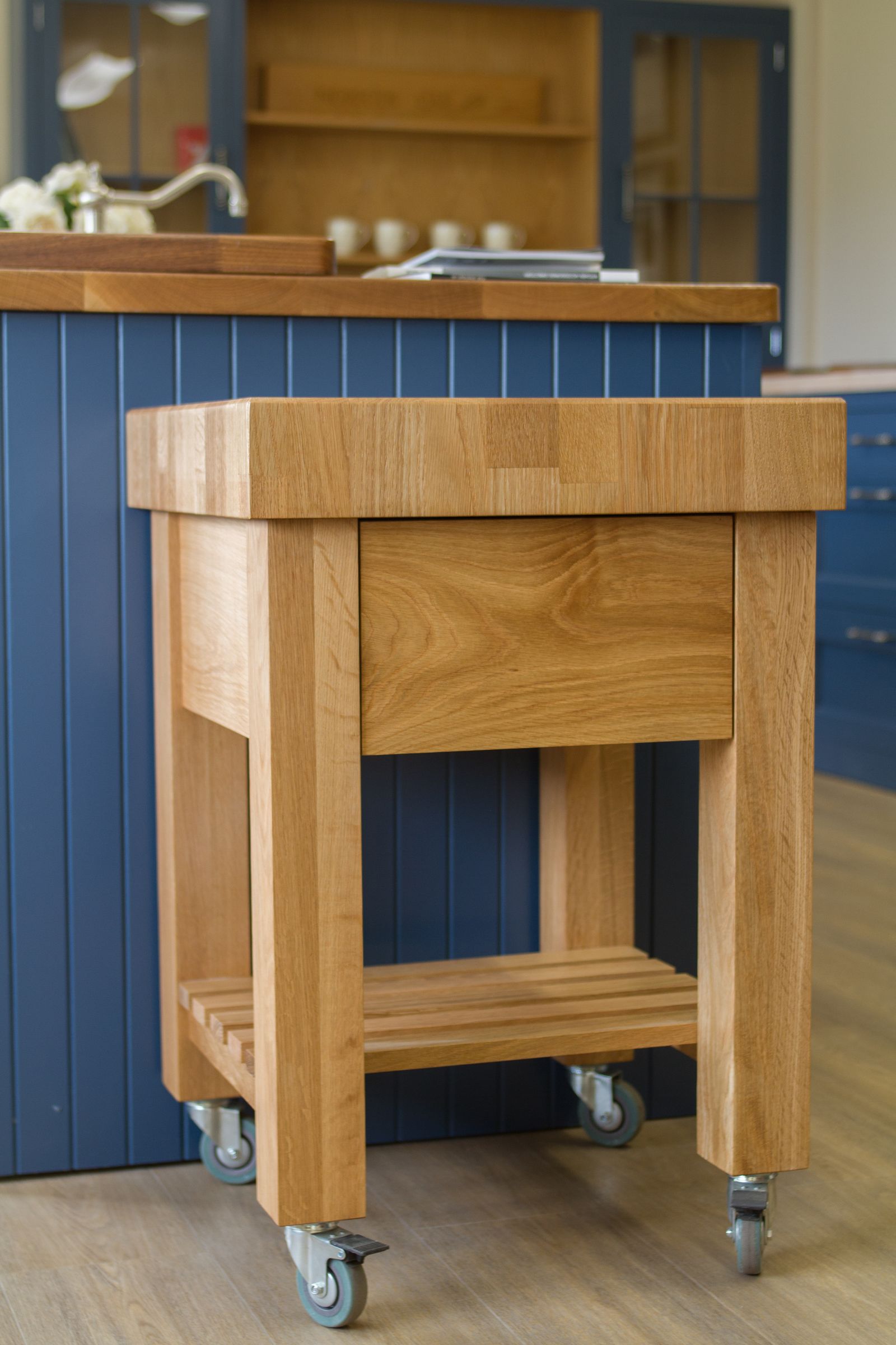 oak end grain trolley Solid oak trolley with drawer, slatted shelf and castors beside a blue kitchen island