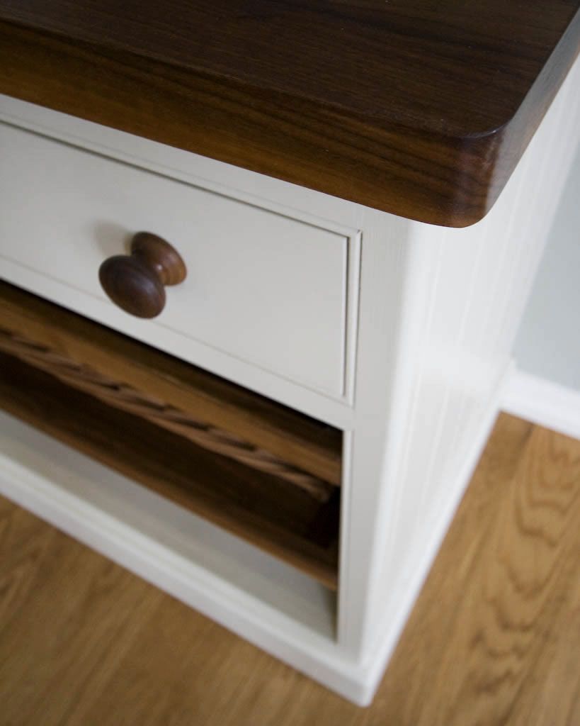 Corner of a white cabinet with walnut worktop and turned walnut knob