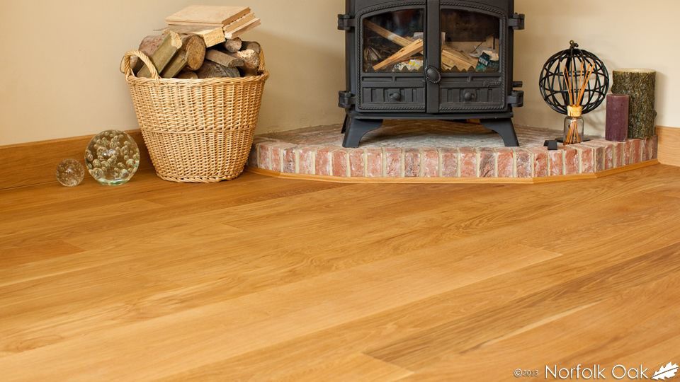 Oak flooring beside a wood-burning stove and log basket