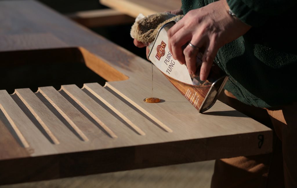 Pouring tung oil over the drainage grooves of a walnut draining board
